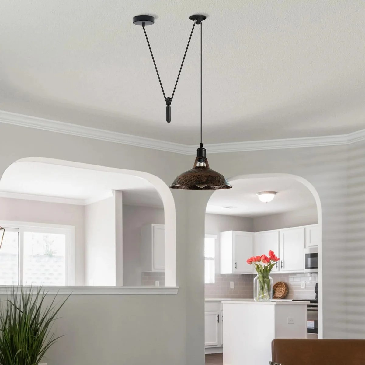 Adjustable metal dome hanging light with industrial pulley system suspended over kitchen island in modern interior