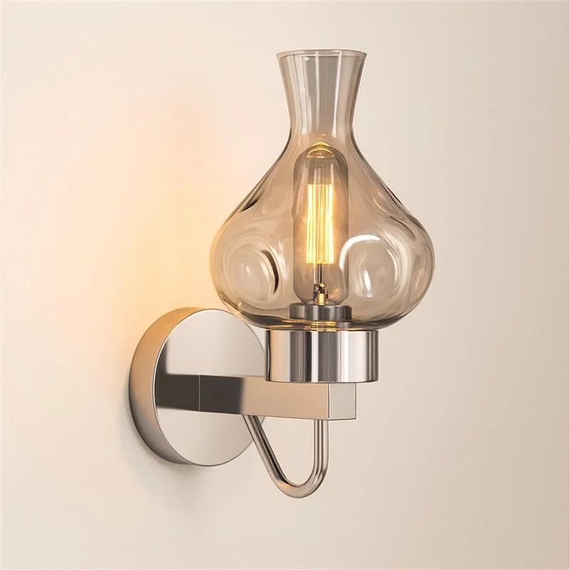 Mid‑century modern dimmable wall sconce with antique brass shade and amber glass bulb housing, mounted on wall