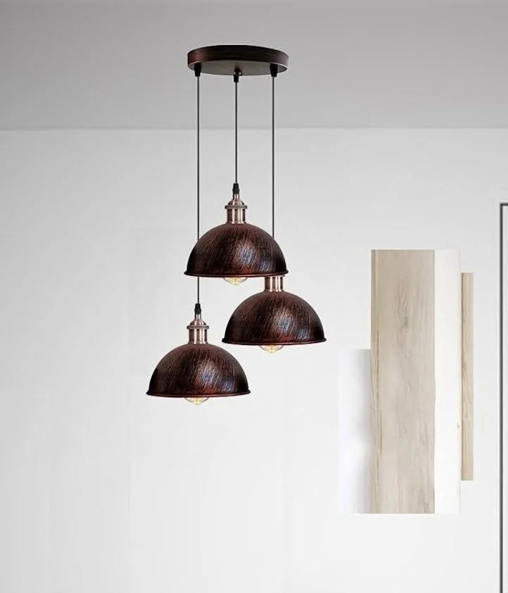 Three vintage industrial ceiling light metal shades with curved design and adjustable cables hanging in a cluster arrangement
