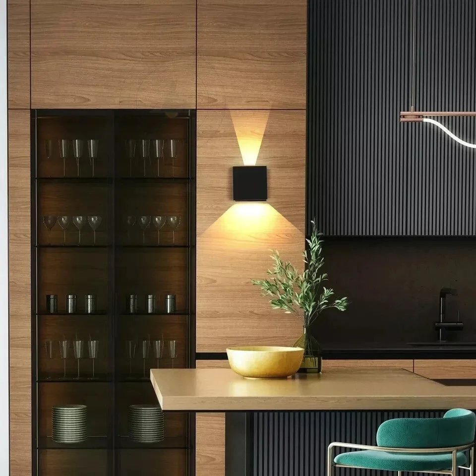 Two black square IP54 rated outdoor lights with warm white up and down beams mounted on a wall at night