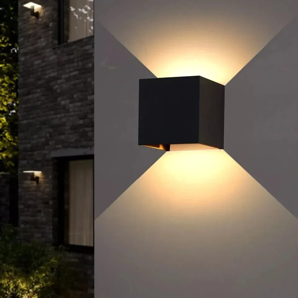 Two black square outdoor LED wall lights with motion sensors mounted on a white wall, emitting warm white light