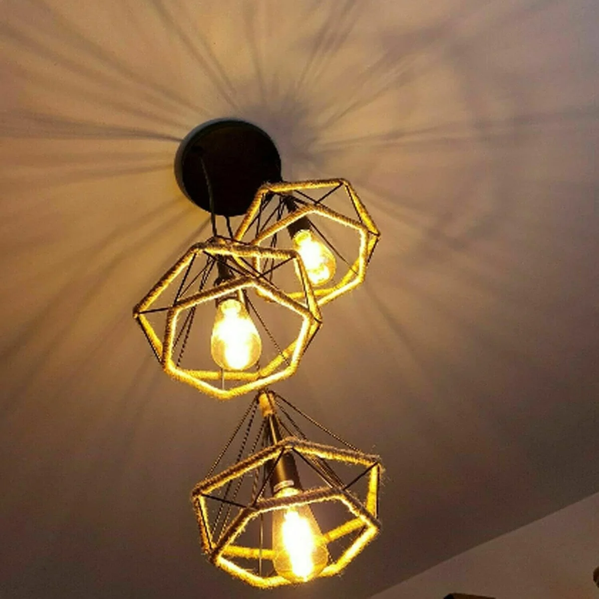 Black metal vintage industrial 3-head adjustable cable pendant light with hemp rope and white interior shades hanging from ceiling