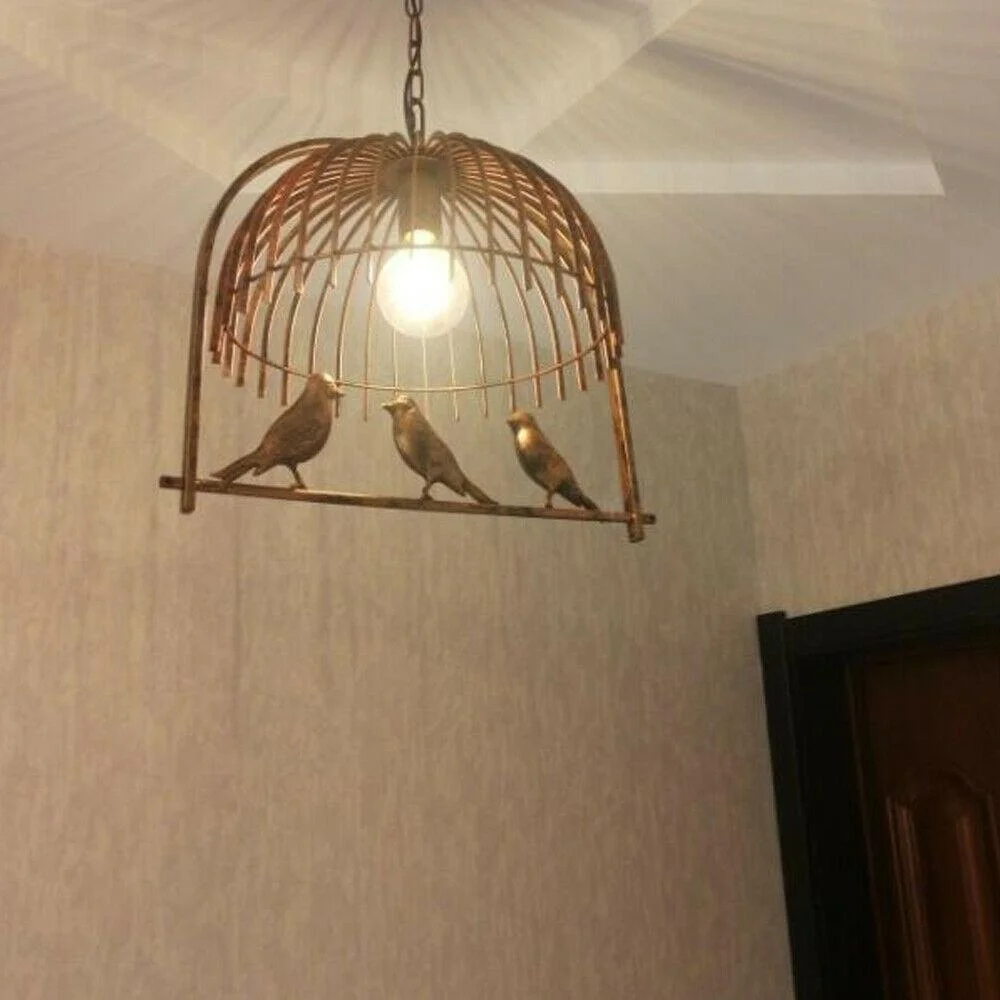 Vintage brass industrial birdcage pendant light with black fabric cord hanging from ceiling canopy
