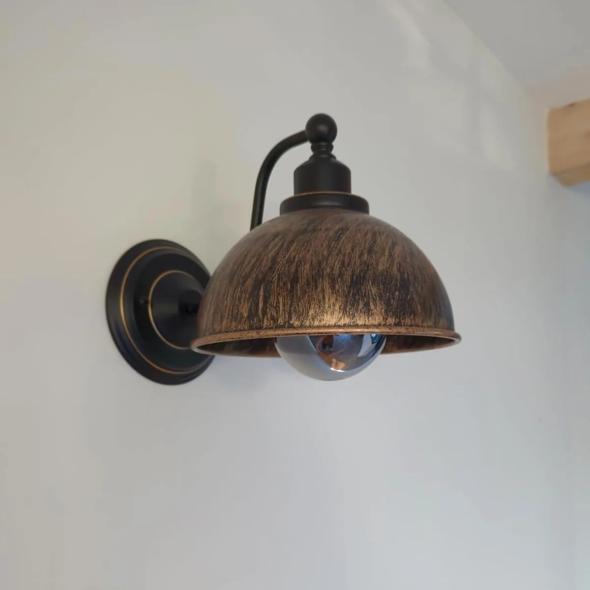 Black industrial wall lamp with metal dome cover and steel arm.