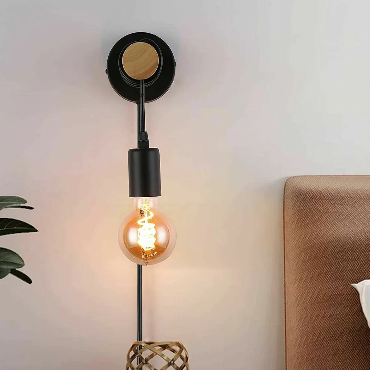 Black industrial wood wall light with metal ceiling plate and plug-in cord, mounted on white wall background
