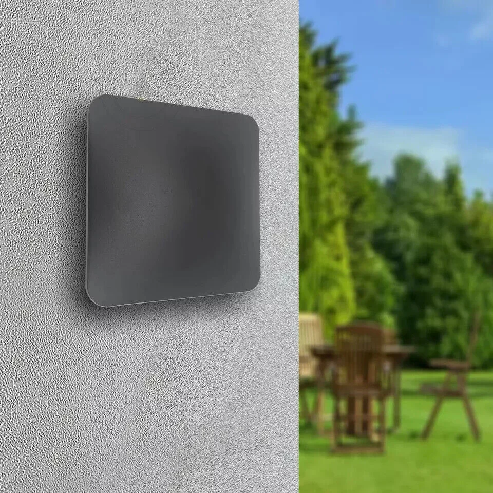 Black modern square warm white LED wall light mounted outdoors on a porch wall, illuminating pathway with soft light