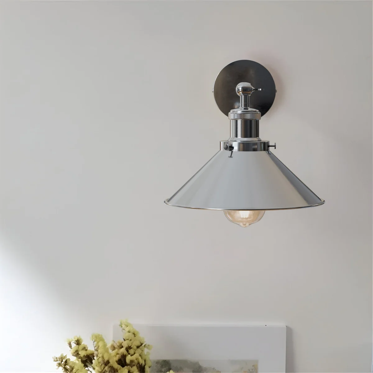 Satin nickel wall light with a cone shade and adjustable arm, mounted on a wall, industrial style.