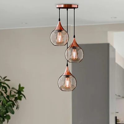 3 light pendant chandelier with three amber glass globe shades and copper finish hanging lights on adjustable cords
