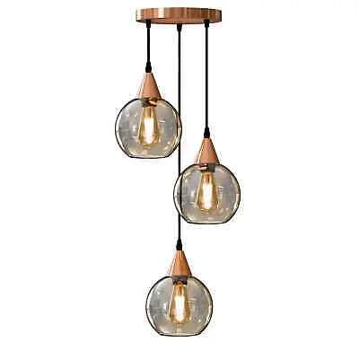Three amber glass globe shades hanging from adjustable cords on a copper E27 bulb pendant light fixture