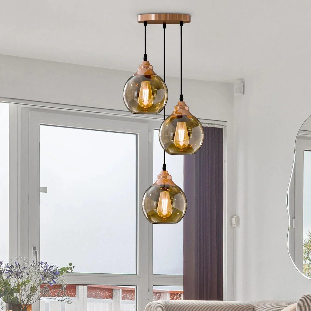 Three-light pendant chandelier with warm copper finish and teardrop glass shades hanging from adjustable cords