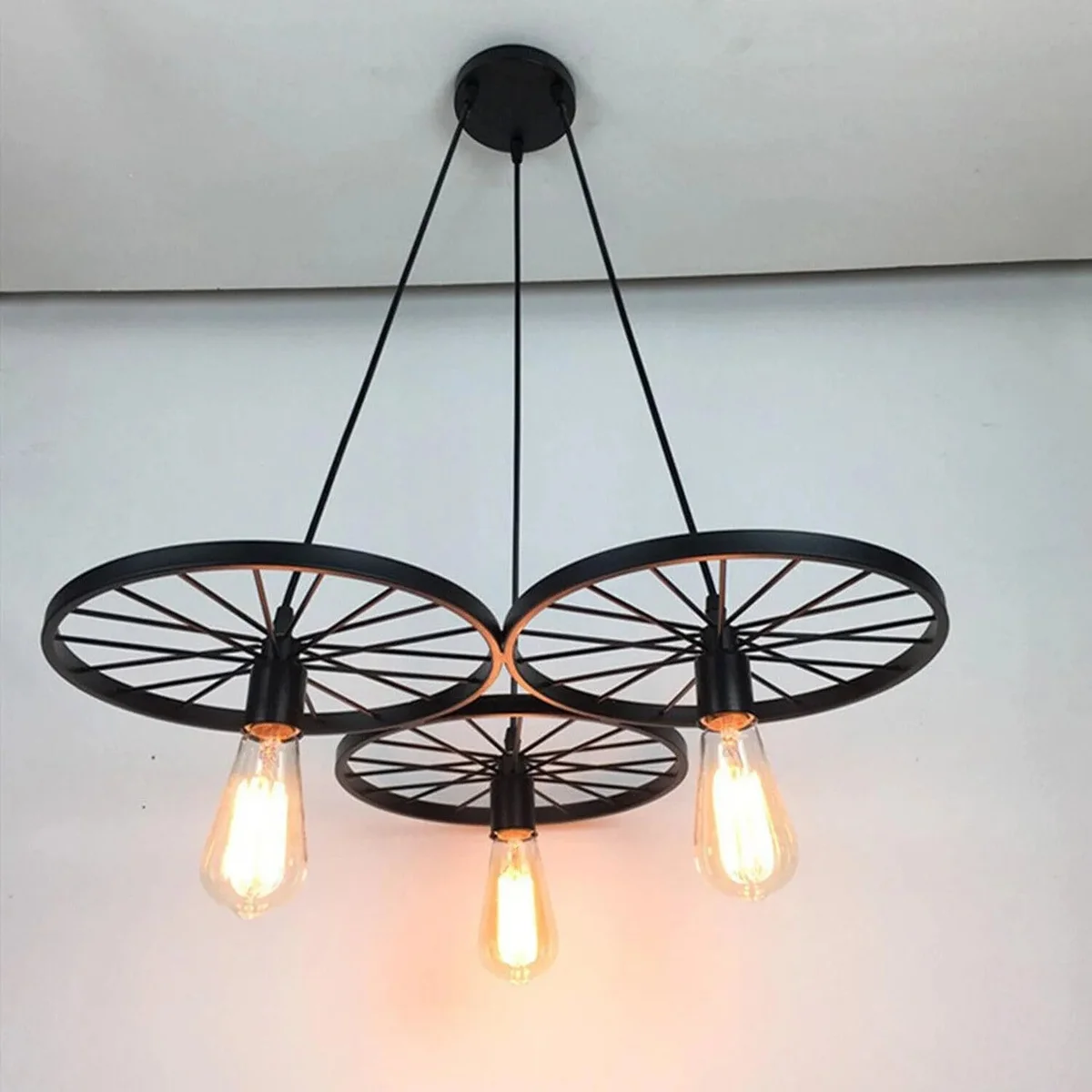 Rustic industrial pendant light with three Edison bulbs on a vintage wagon wheel metal frame hanging fixture