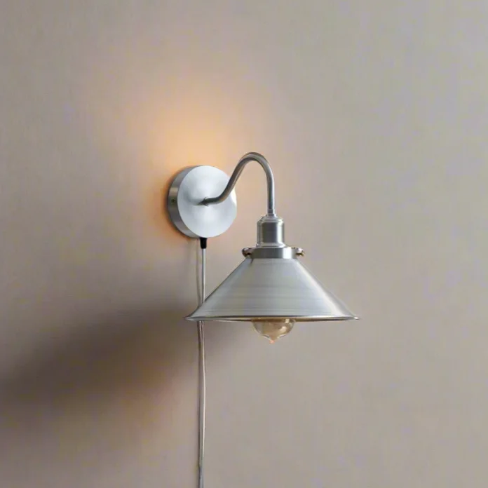 Retro industrial wall sconce with satin nickel swan neck arm, cone shade, and on/off switch, mounted on white wall