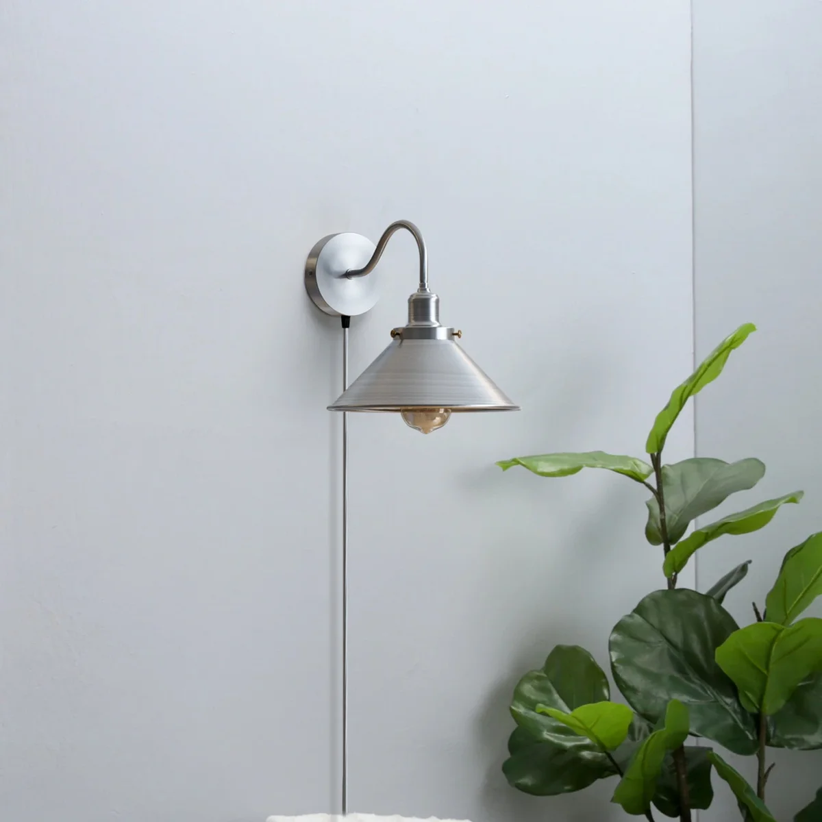 Satin nickel swan neck wall light with cone shade, metal finish, and on/off switch, mounted on white wall with 2m cord