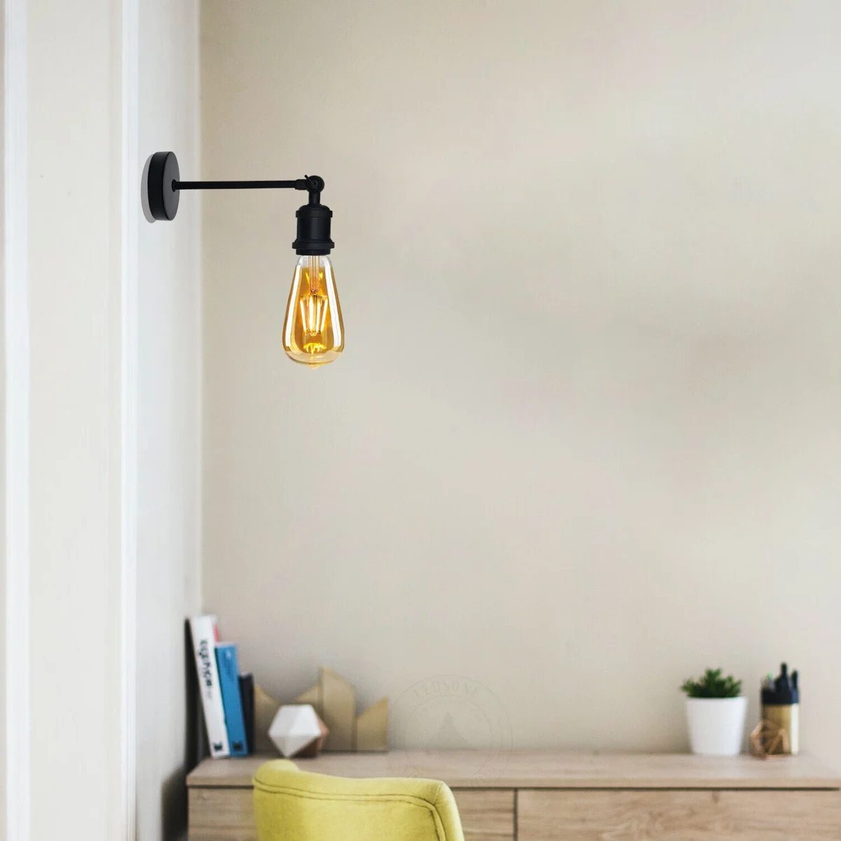 Industrial wall light with adjustable arm and antique brass finish mounted on a wall in a cozy indoor setting
