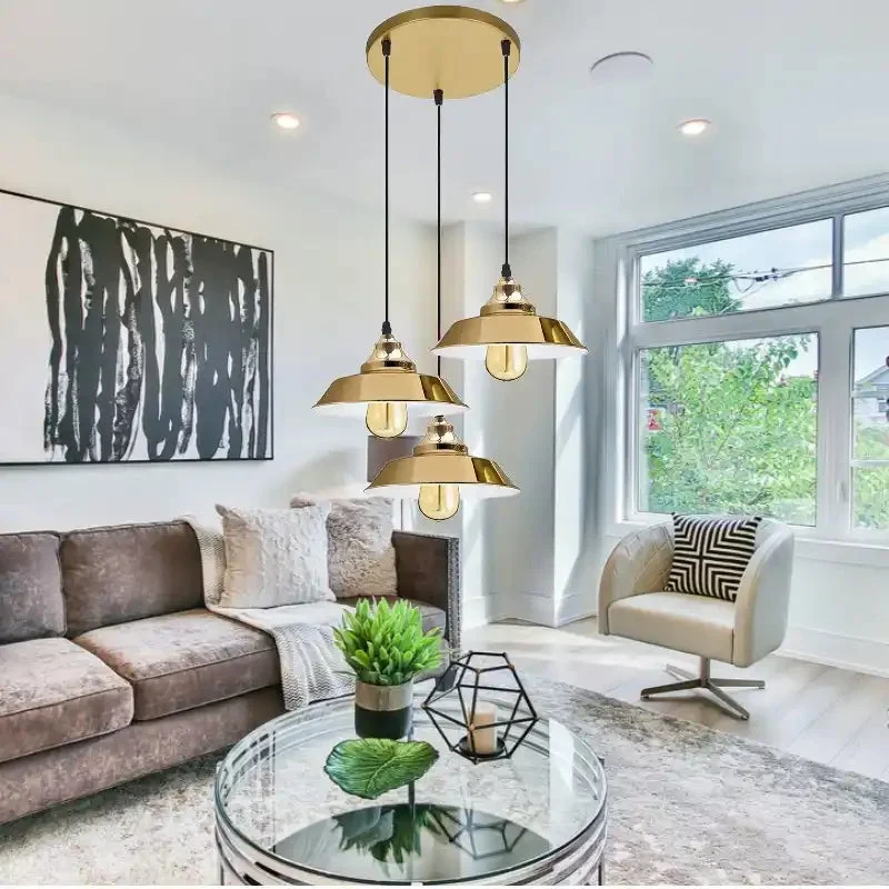 Three retro metal pendant lamps with yellow brass finish and adjustable cables hanging from a ceiling rose