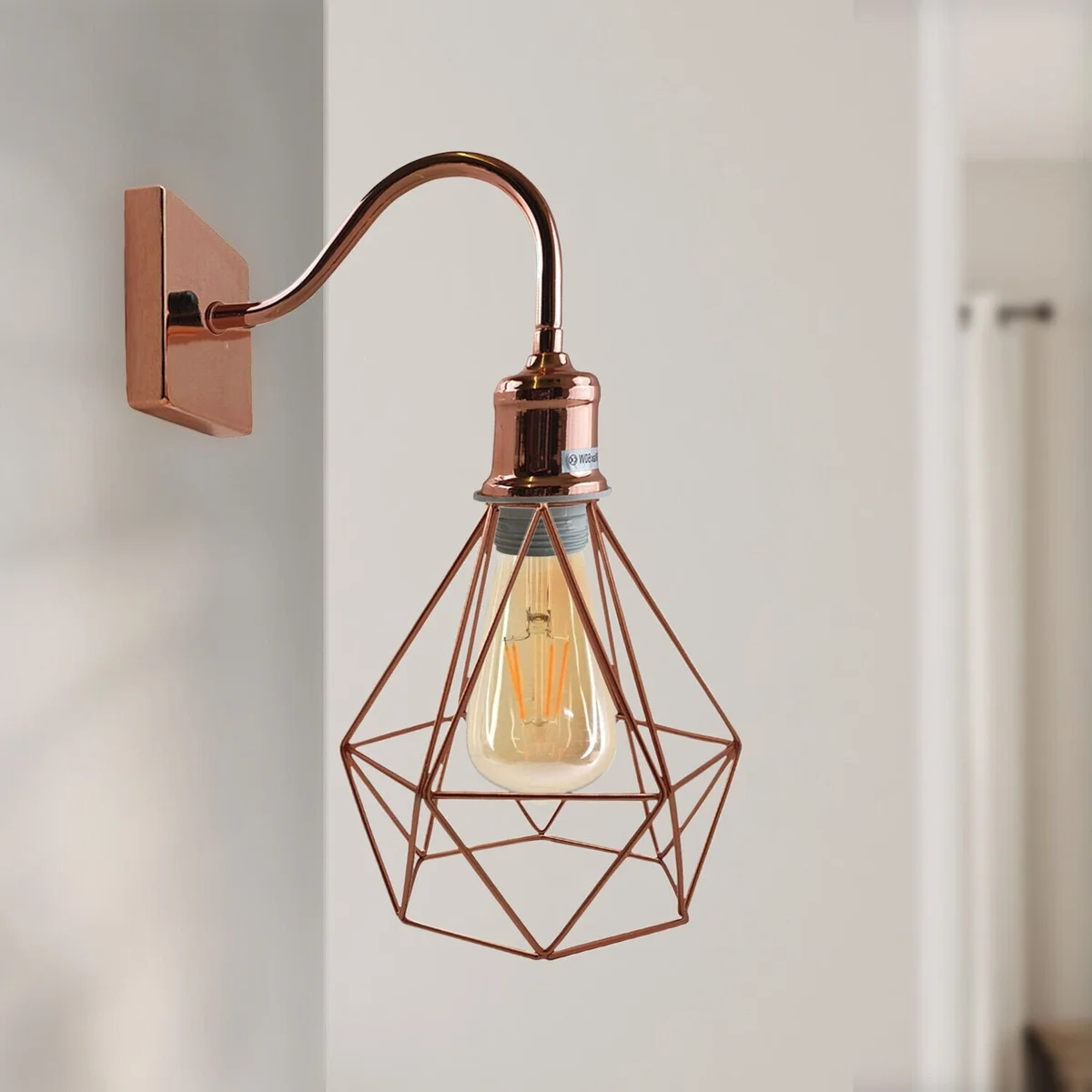 Rose gold industrial metal E27 wall light fitting with cage design mounted on a white wall in a modern vintage style