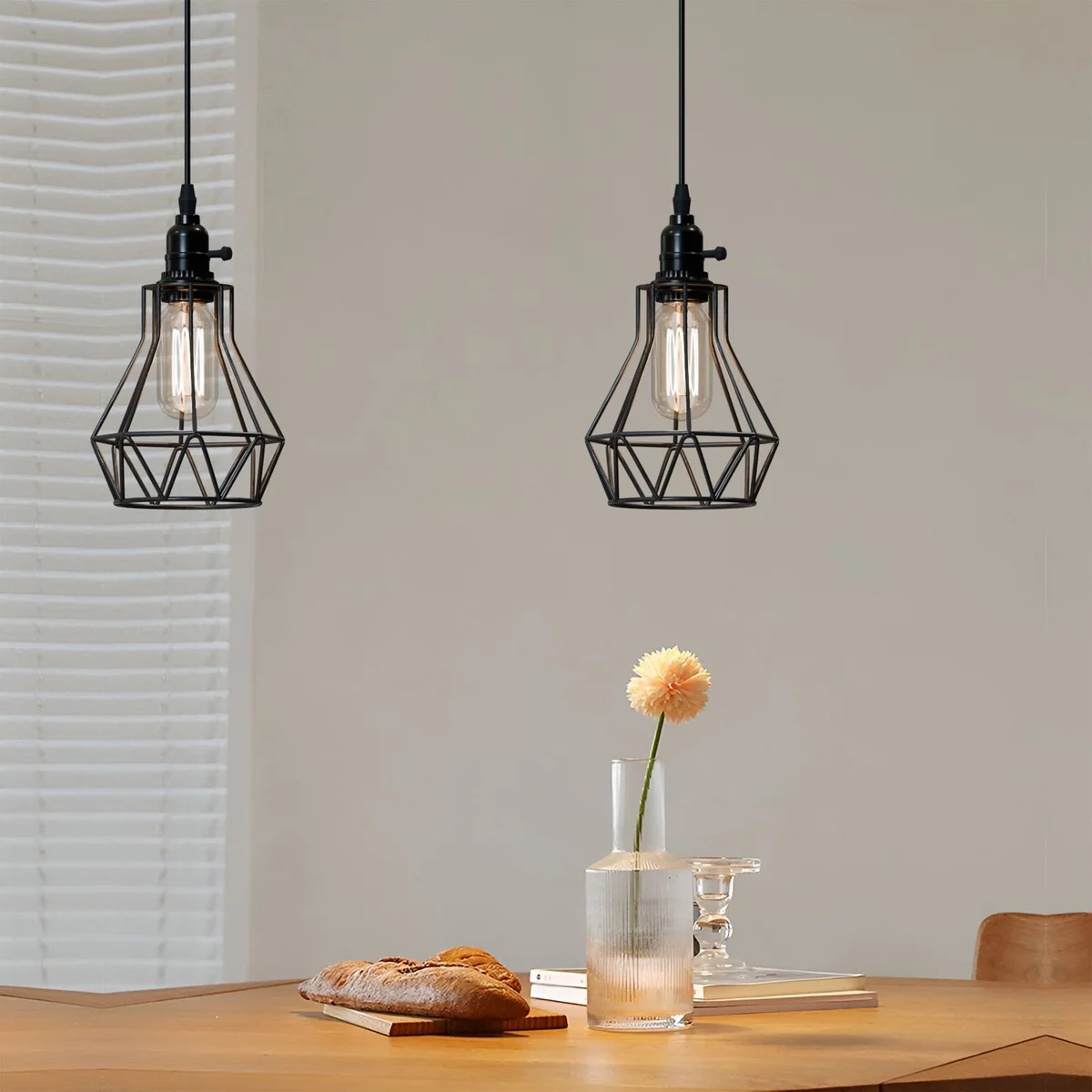 Black industrial pendant light with geometric metal cage, hanging above a kitchen island, showing adjustable cable and switch