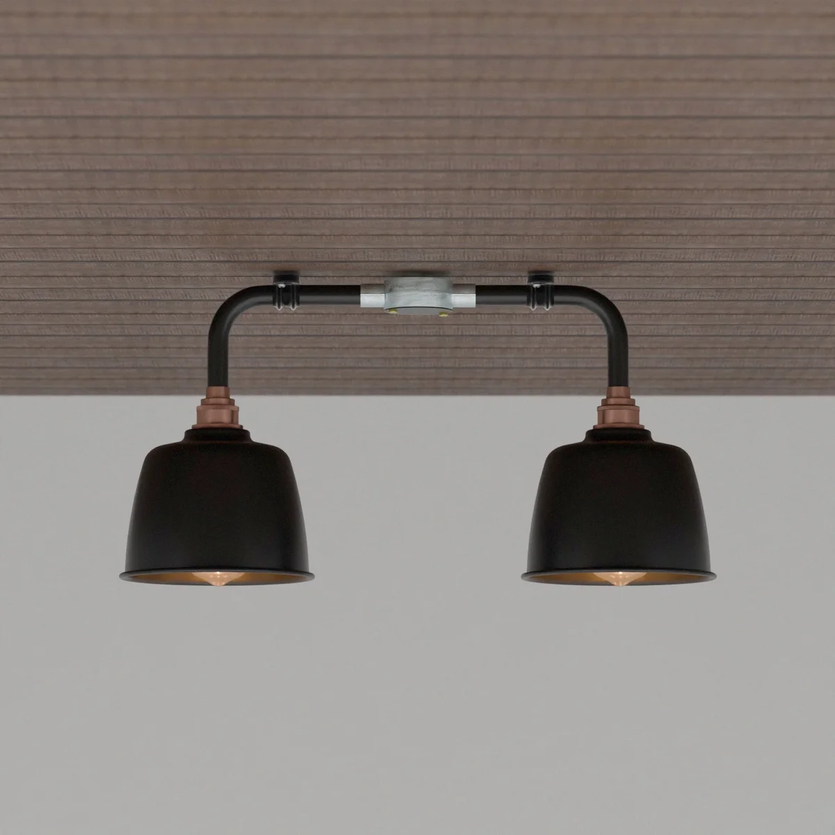 Black vintage industrial ceiling light with two angled downlight fixtures and copper fittings mounted on a wall