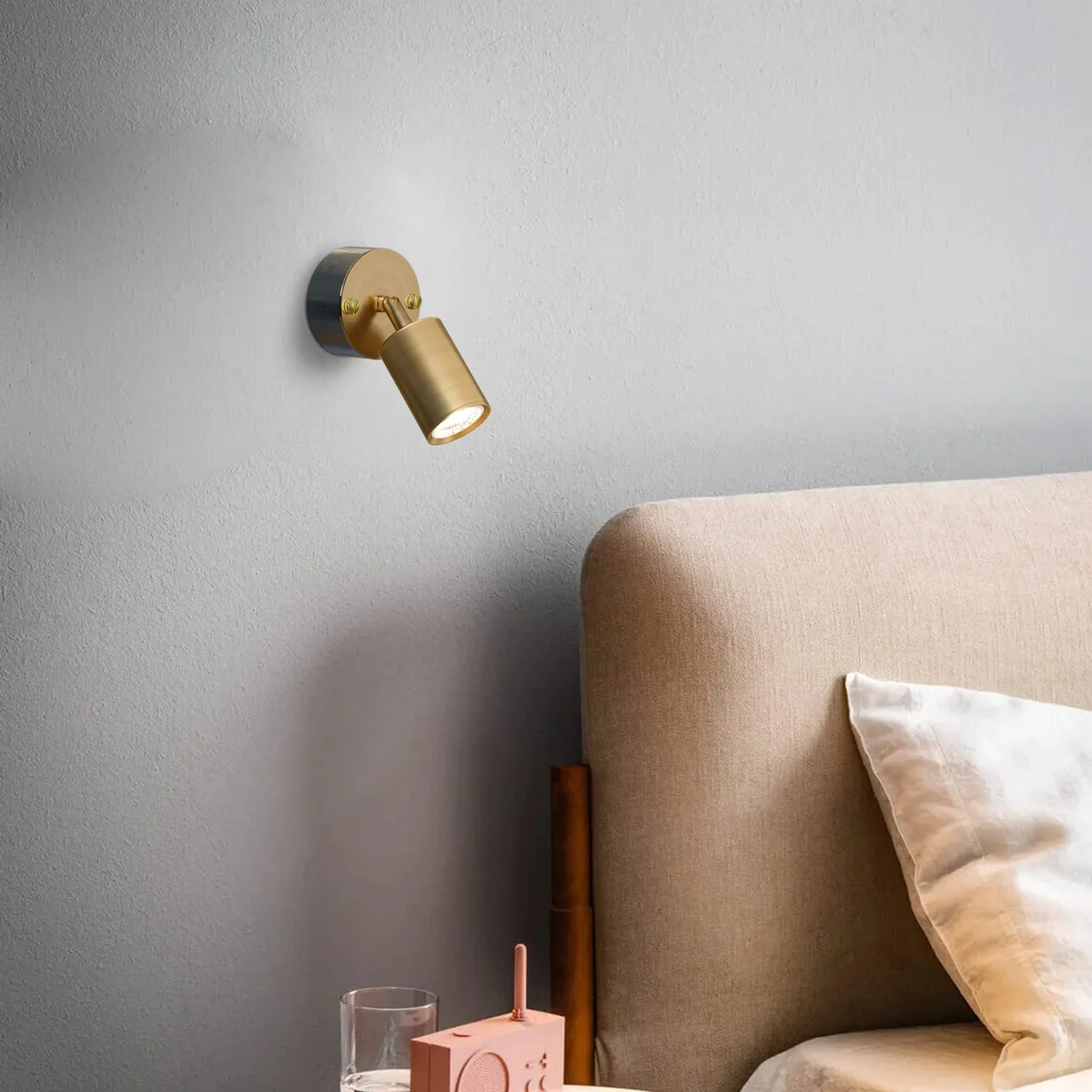Yellow brass rotatable metal conduit light fixture with cylindrical spotlight and galvanized steel loop-in box mounted on wall