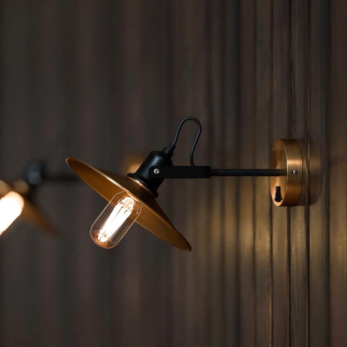Industrial adjustable corded electric wall light with metal swivel arm and E27 bulb socket in a sleek black finish