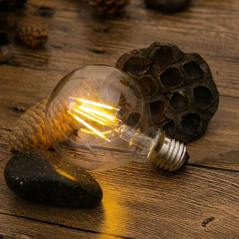 8W LED globe bulb with amber glass, vintage filament, E27 screw base, glowing warm white light on dark background