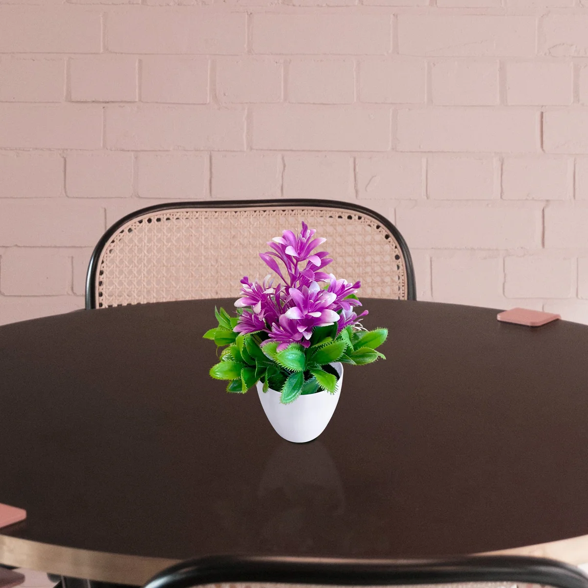 Bright indoor fake flowers in a small plastic pot with green leaves, ideal for low-maintenance indoor decor