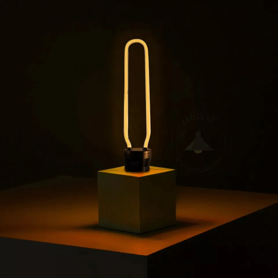 Retro vintage LED filament bulb with warm yellow glow and E27 Edison screw base on white background