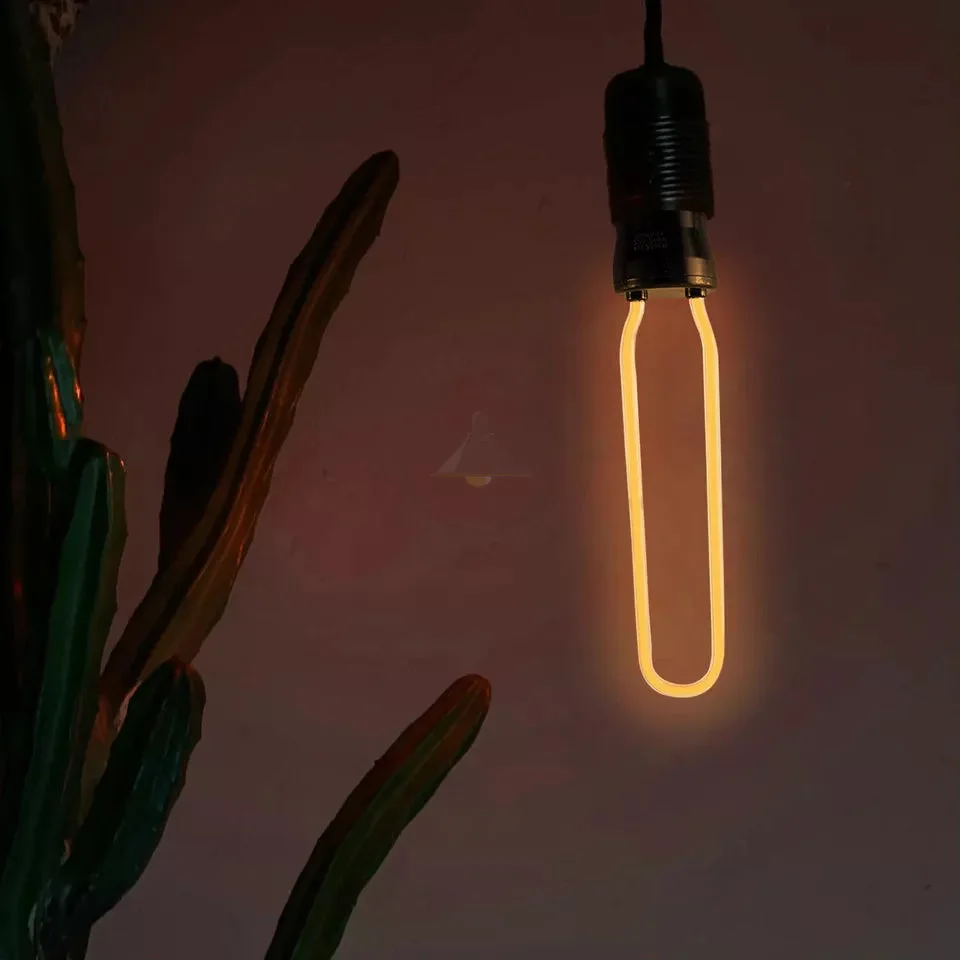 Retro vintage Edison E27 LED light bulb with visible flexible filament and warm yellow glow on a white background