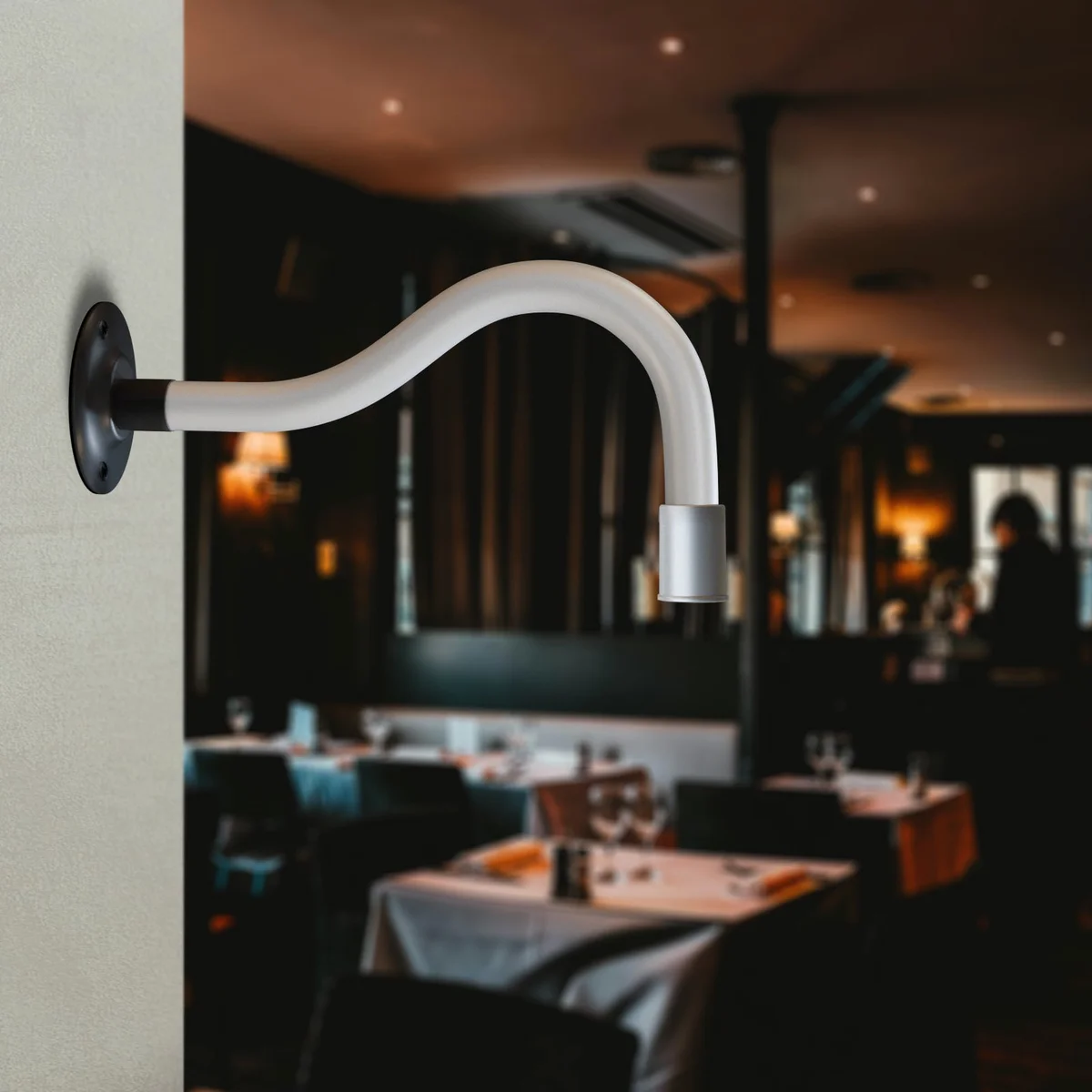 Flexible LED wall light with curved metal gooseneck arm mounted on a white wall, emitting cool white light