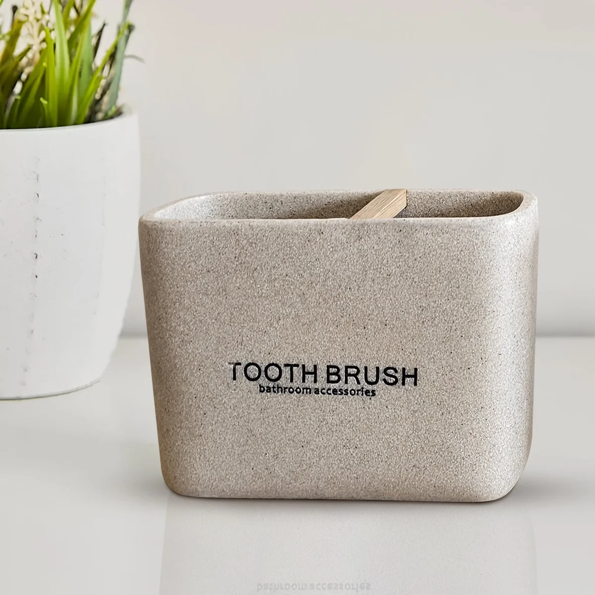 Modern bathroom accessory set with stone effect resin lotion dispenser, toothbrush holder, and tumbler on white background