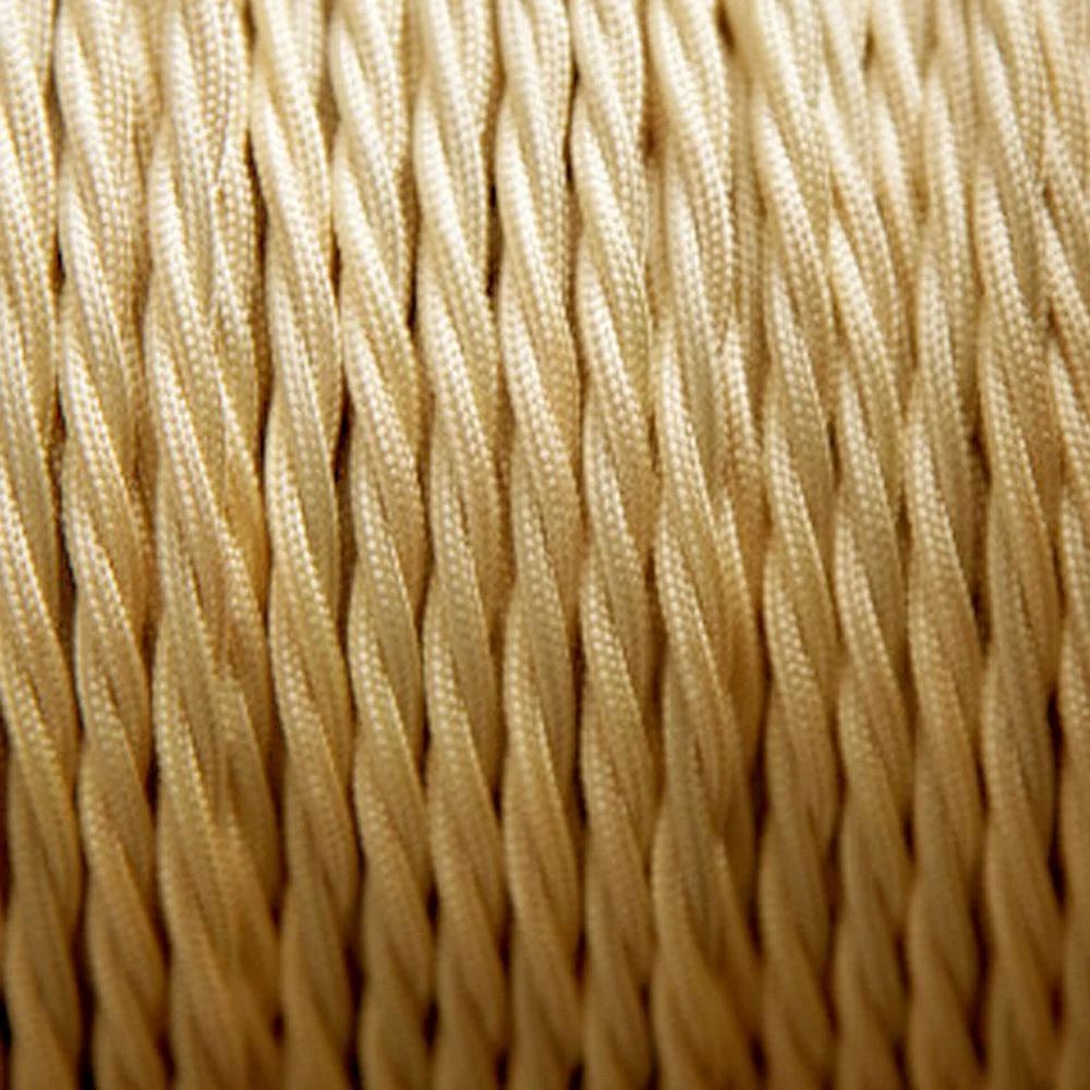 Light gold twisted fabric lamp cord coiled on white background showing silky braided texture and vintage style