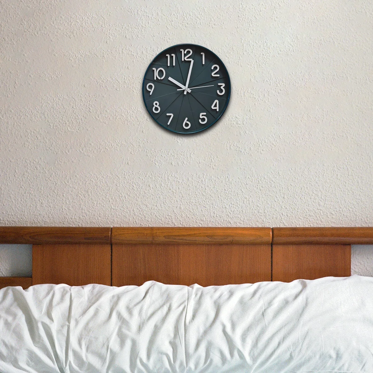Round black non ticking clock with white numbers and hands on black background, sleek plastic and tempered glass face