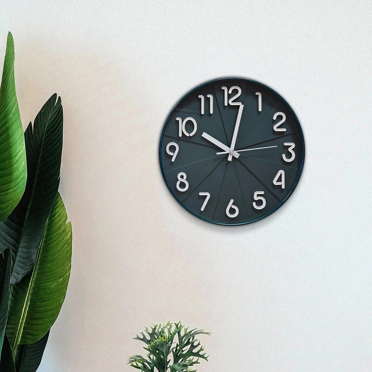 Round black silent wall clock with white numbers and hands on black background, sleek plastic and tempered glass face