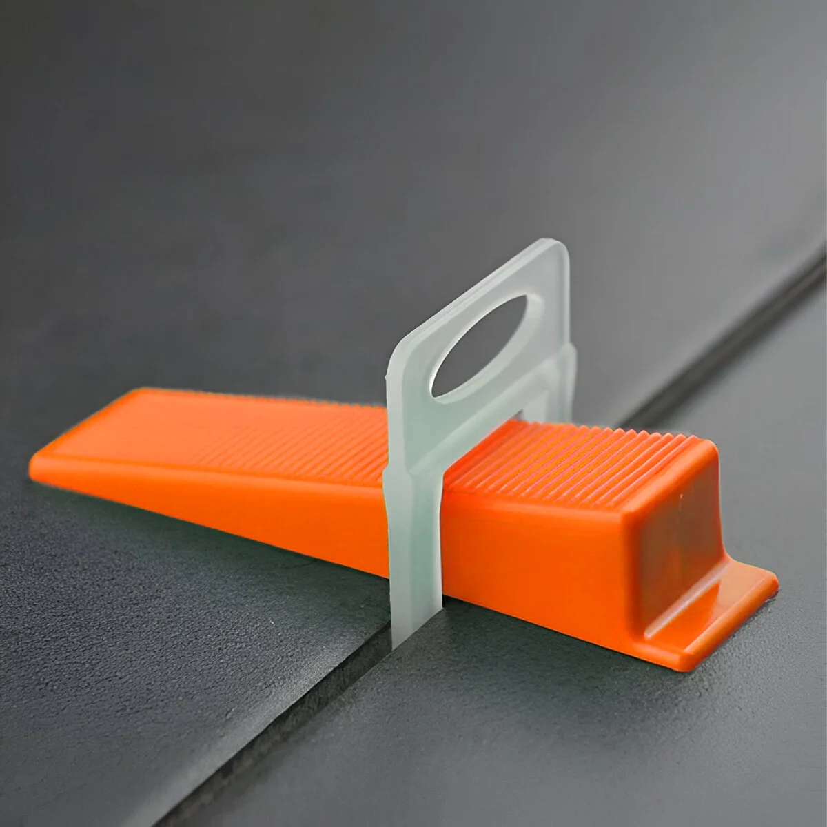 100 yellow, red, and orange T-shaped tile leveling wedges arranged in a pile for floor and wall tile installation