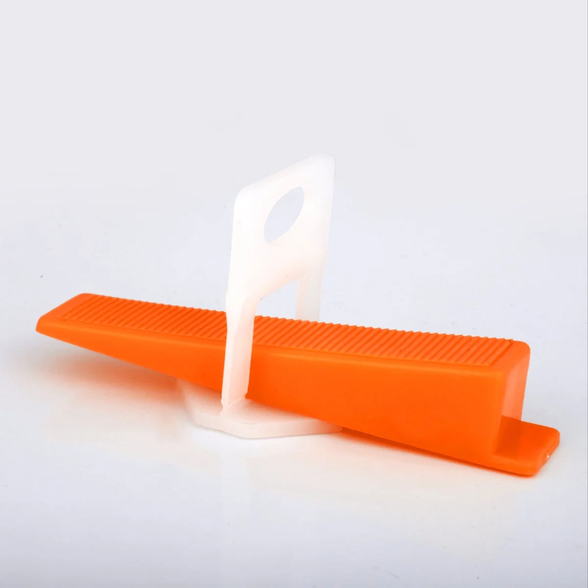 100 yellow, red, and orange T-shaped tile leveling wedges stacked, showing size and shape for floor and wall tiling projects