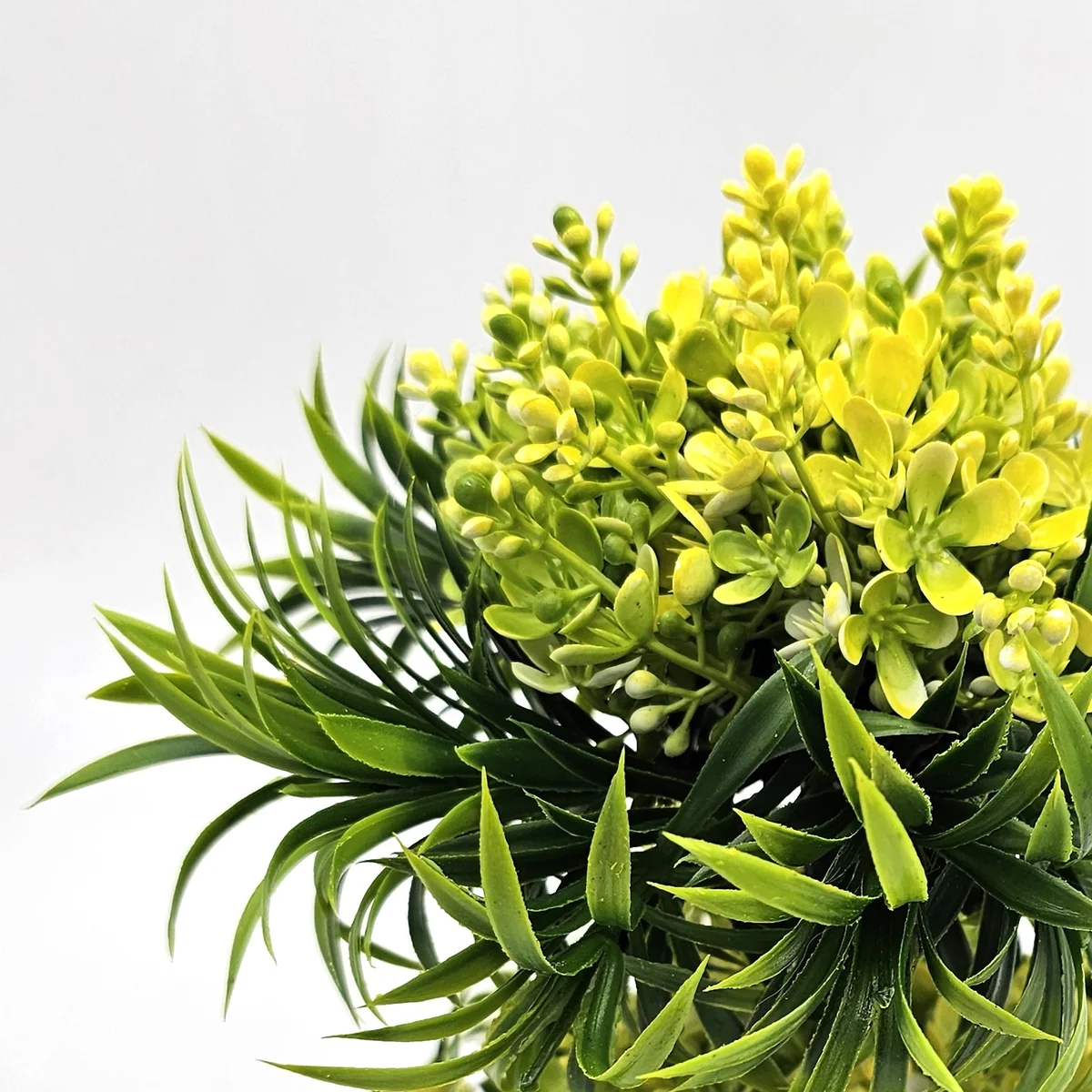 Two small plastic bonsai trees in black pots displayed on a wooden surface with a white background