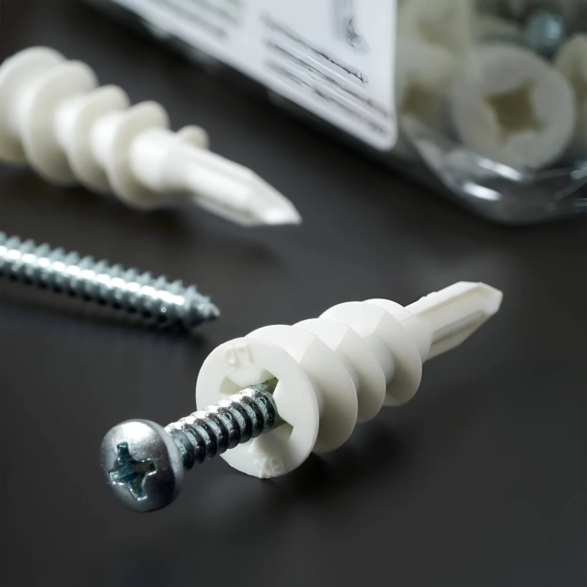 Pack of 100 white gypsum board screws with flat heads for drywall and plasterboard fixing, self-drilling design visible