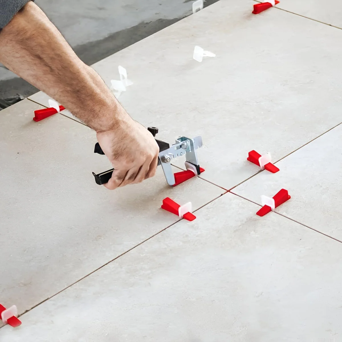 Tile spacers tool with ergonomic orange and black pliers and reusable leveling wedges for precise tile alignment
