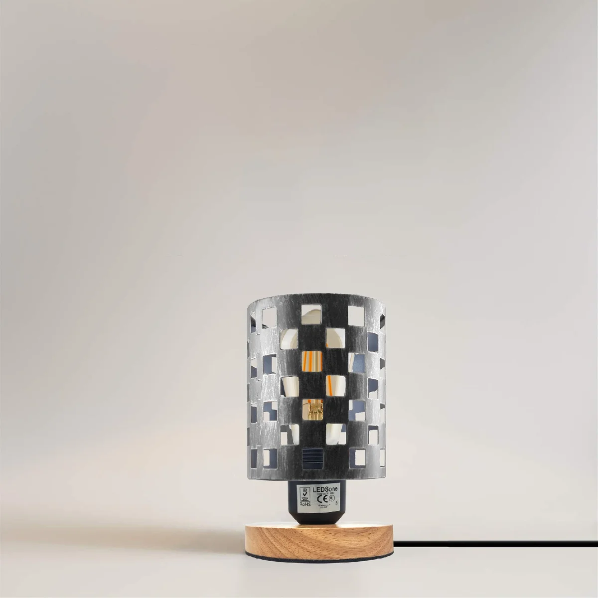 Antique brass bedside lamp with metal wire cage shade and natural wood base on a white background