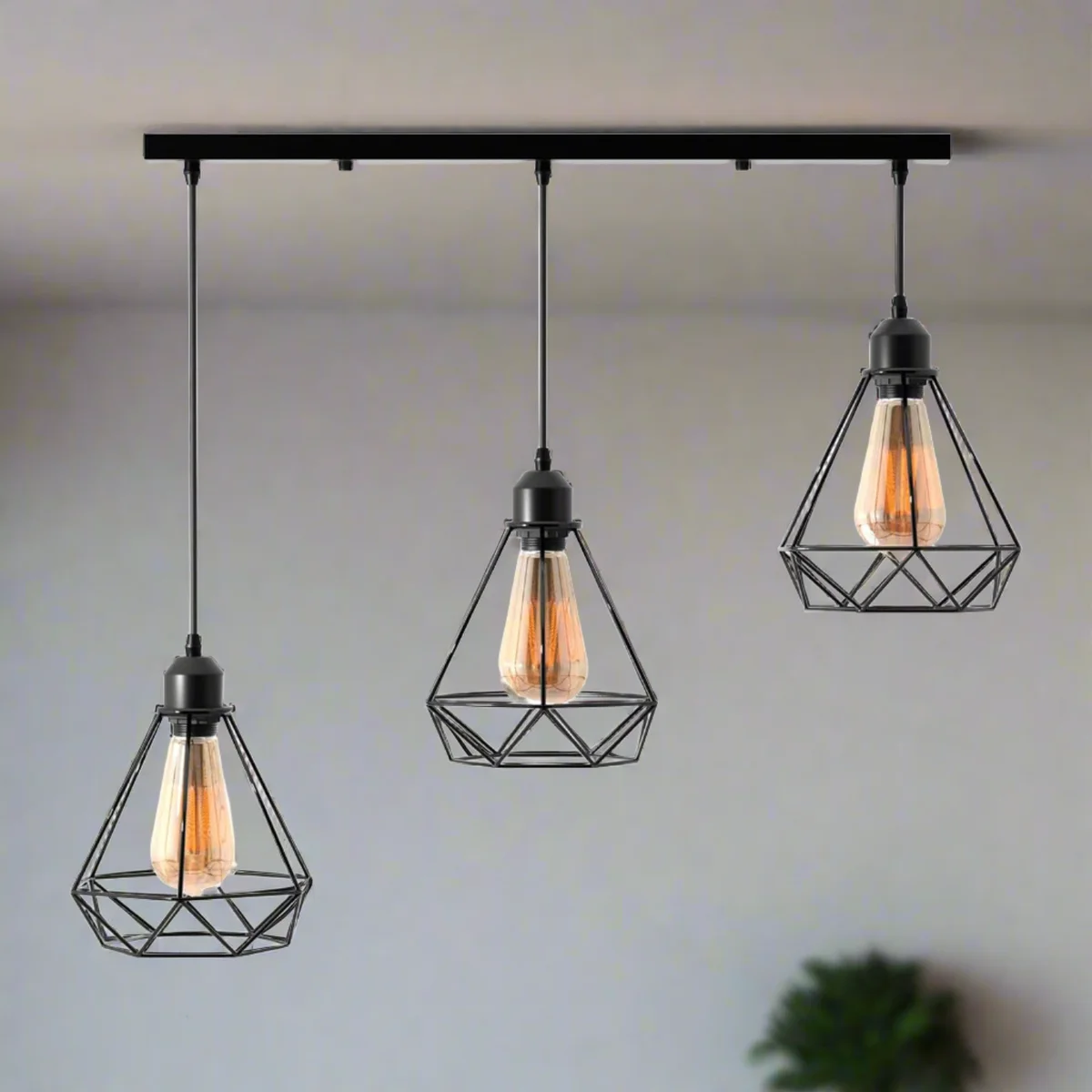 Black industrial pendant light with three diamond wire cage shades hanging from adjustable cables on white ceiling