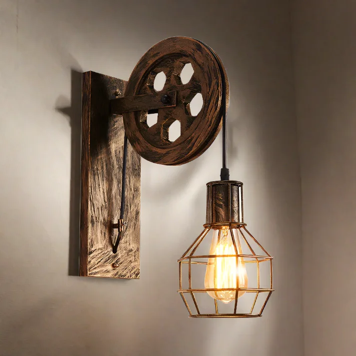 Industrial vintage wall sconce with wooden beam, iron pulley wheel, and protective wire cage shade for E27 bulb.
