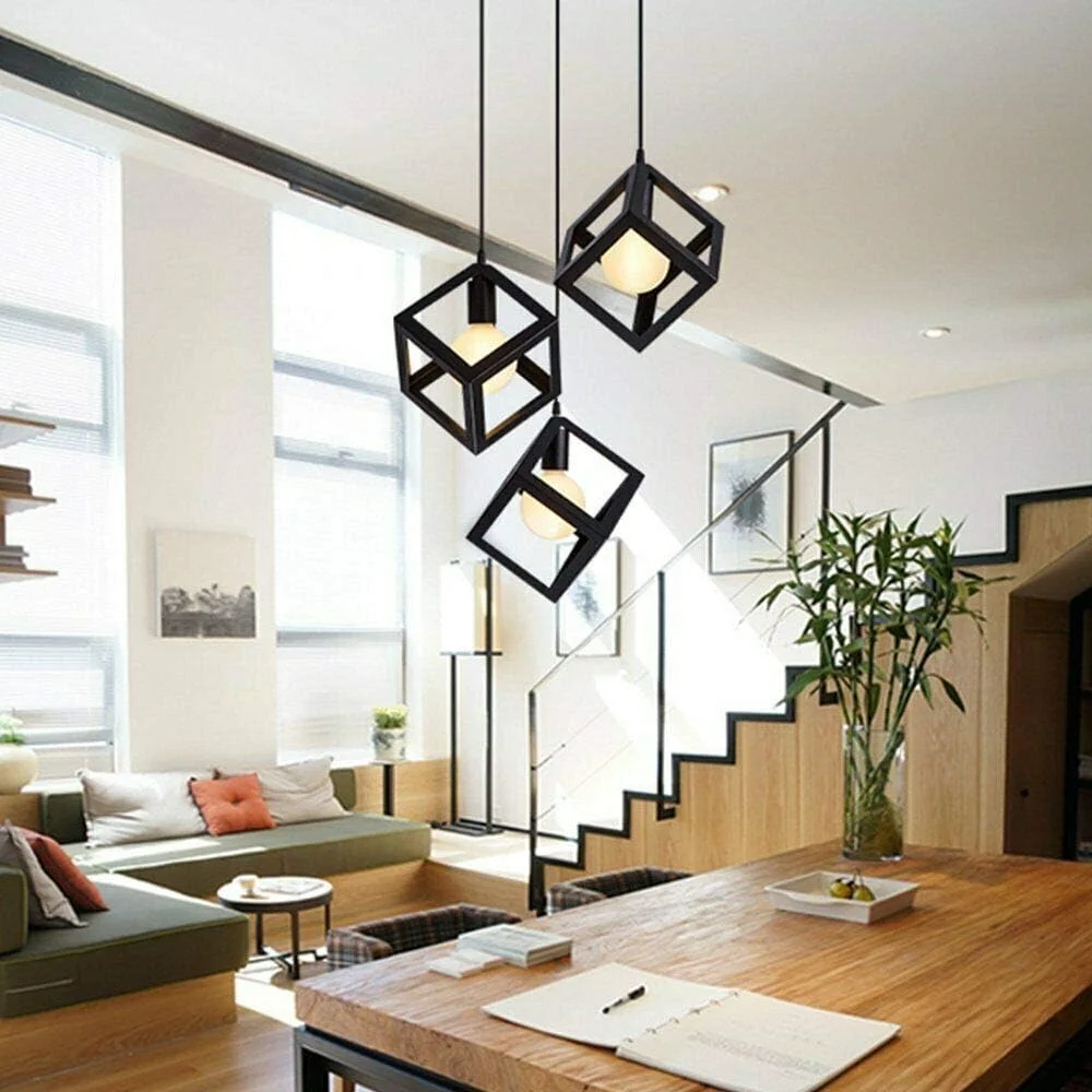 Three head black wire cage pendant light with angled metal frames and hanging cables against a white background
