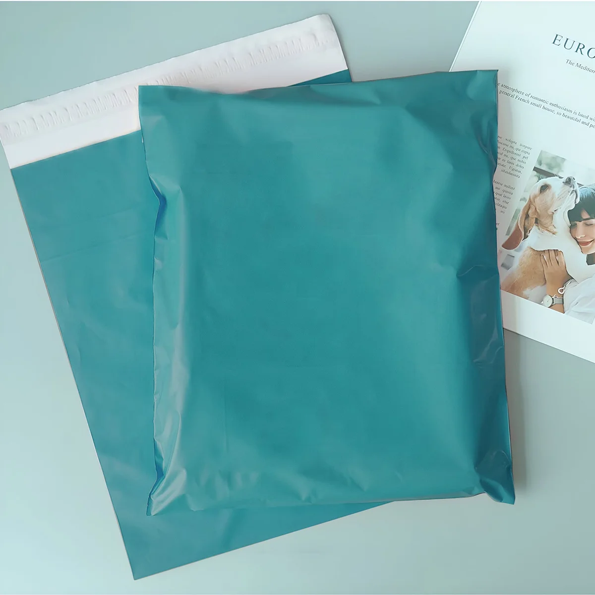 Stack of pink, light green, and cyan blue polyethylene mail bags with self-adhesive seals, 28x42cm size visible