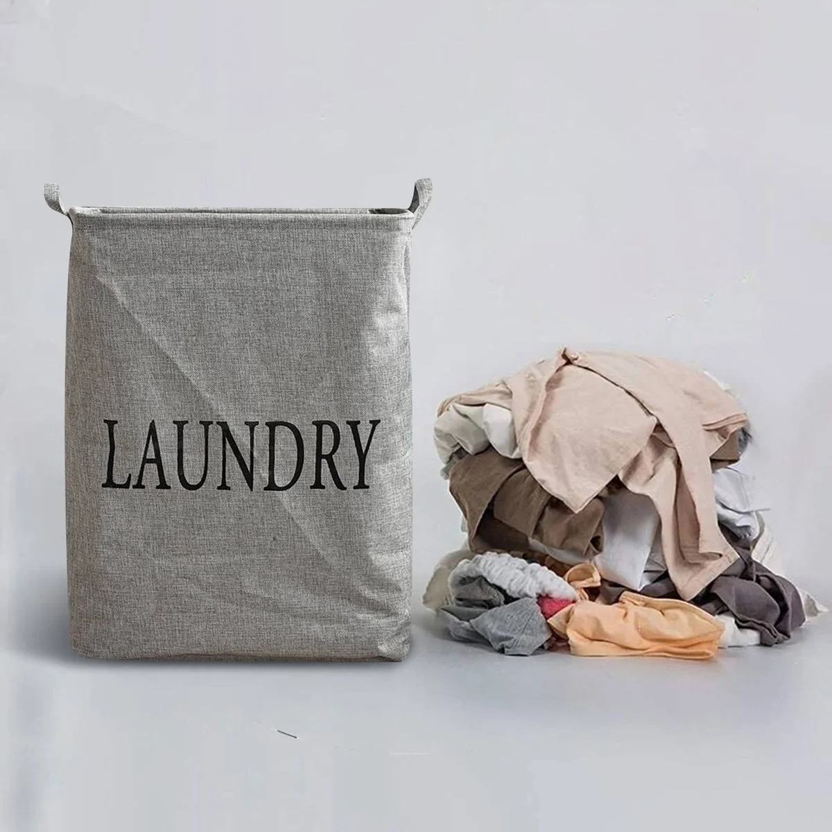 Foldable cotton laundry bag with drawstring, square shape, handles, standing freestanding in a bedroom corner