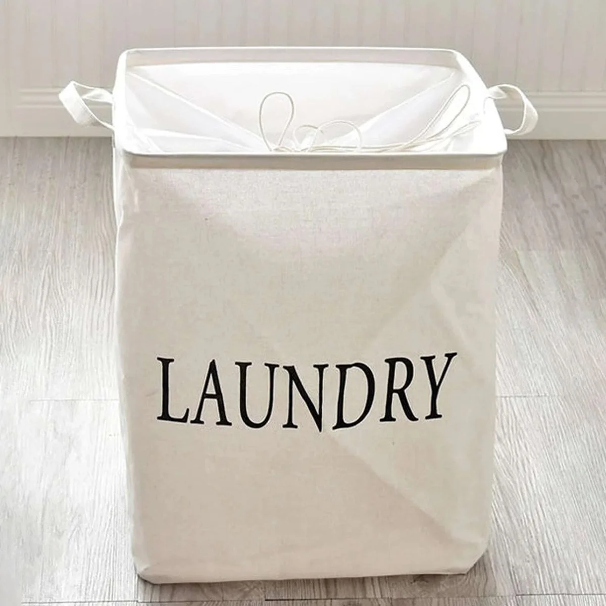 Foldable waterproof laundry bag in beige linen and cotton with handles, standing upright and partially open showing spacious interior