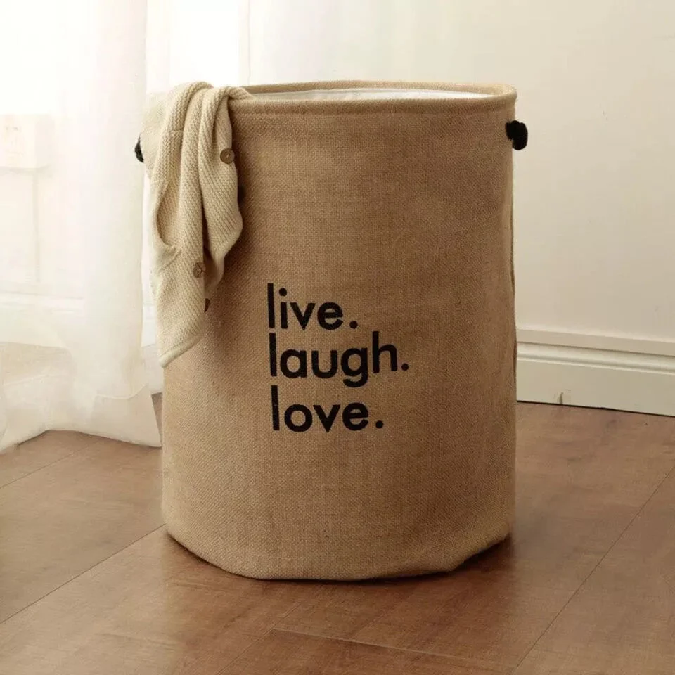 Foldable round jute laundry bag with handles, standing upright, showing spacious interior and waterproof lining