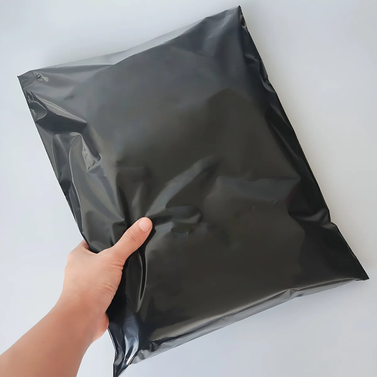 Stack of large black polyethylene mailing bags 40x55cm with self-adhesive waterproof closure for secure packaging