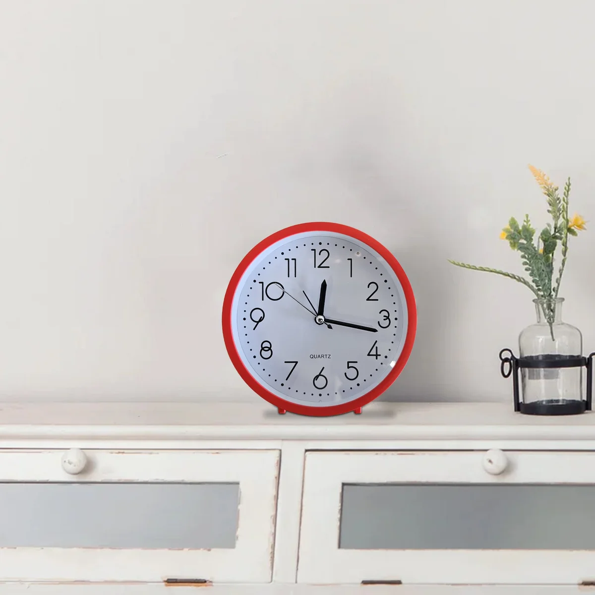 Retro alarm clock with white numerals, black frame, and soft night light, shown mounted on a white wall.