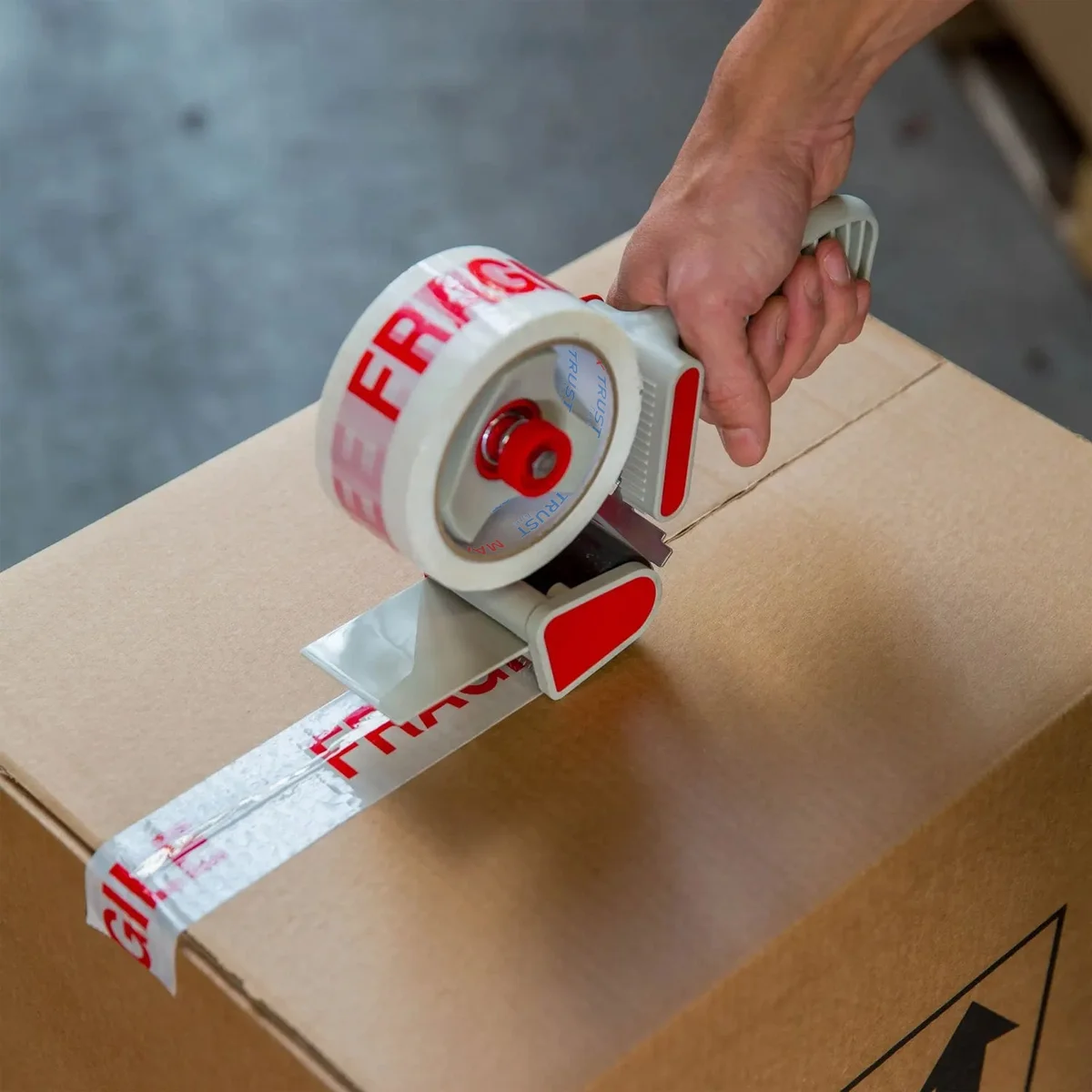 Roll of heavy duty packing tape with red and white fragile print, designed for secure carton sealing and protection