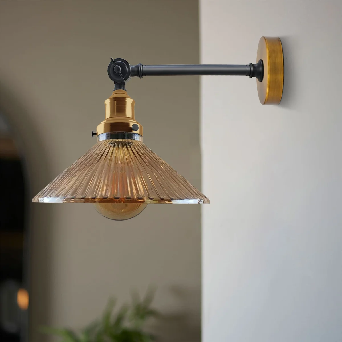 Amber glass wall light with ribbed shade, adjustable brass holder, and black arm mounted on wall